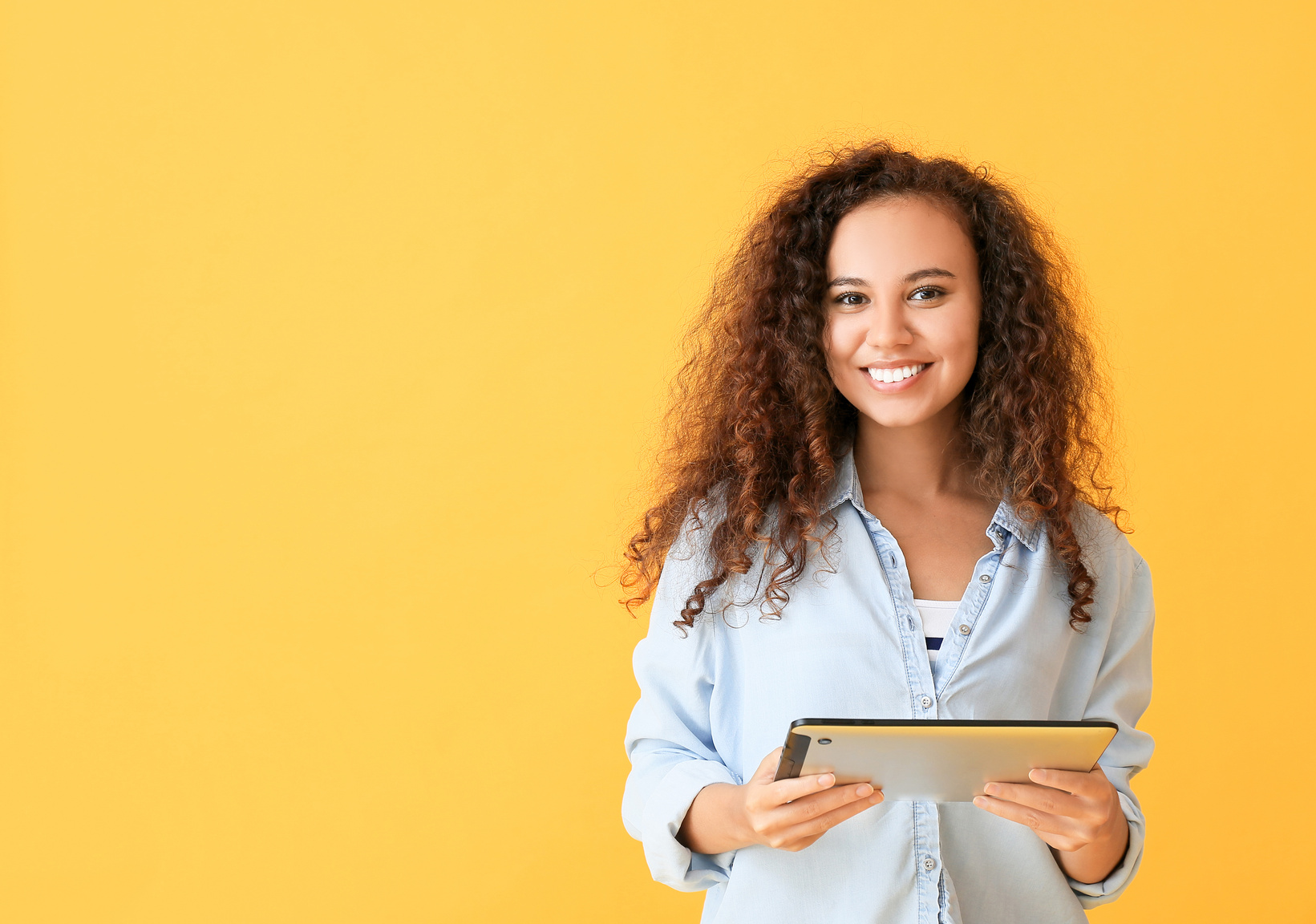 Young Woman with Tablet Computer on Color Background